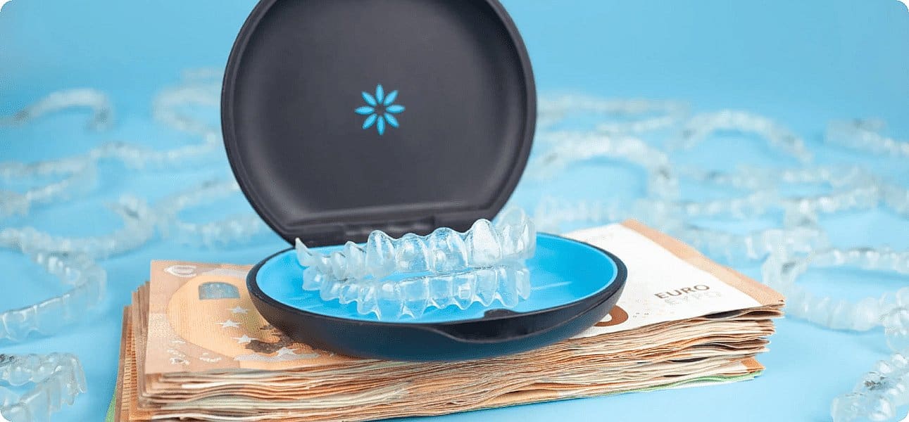 Against a blue backdrop, clear dental aligners in an open case sit atop euro banknotes, with more aligners scattered nearby. This scene subtly suggests the Invisalign cost at Winks Orthodontics
in Prosper and Colleyville, TX