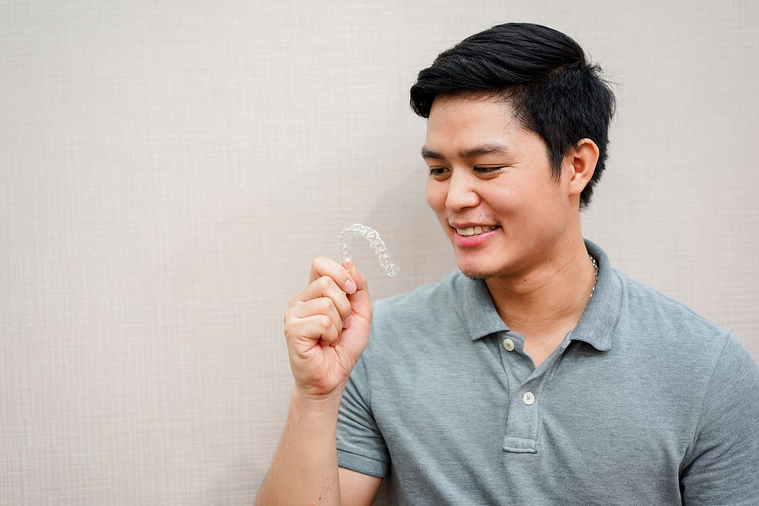 A man smiles while holding an invisalign in front of his mouth and getting cheap invisalign cost at Winks Orthodontics
in Prosper and Colleyville, TX