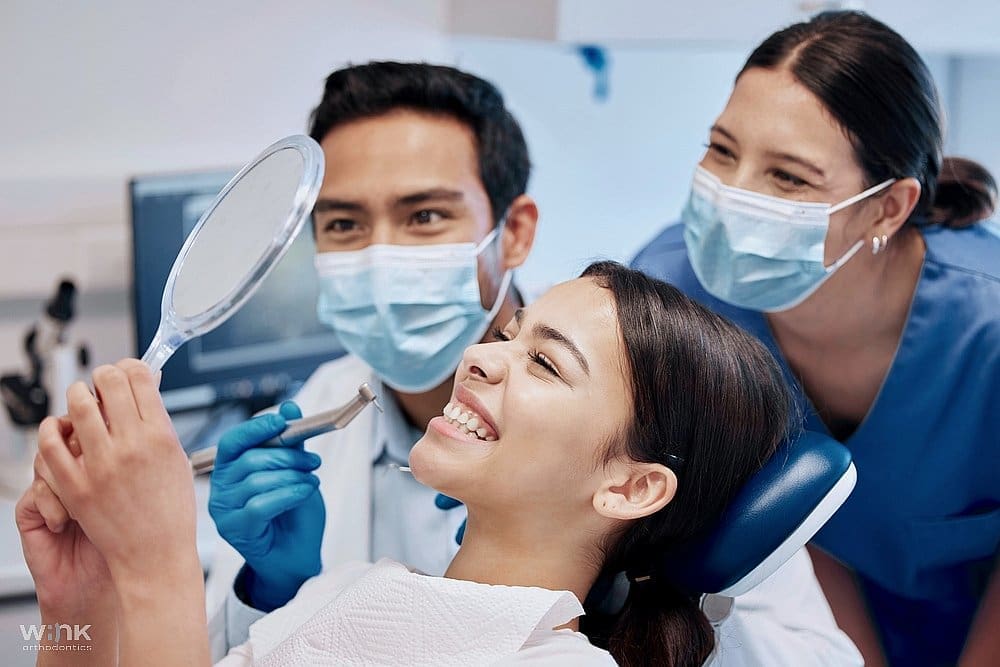 A happy patient sitting with dental professionals after a successful treatment for how to fix overbite in Prosper and Colleyville, TX.