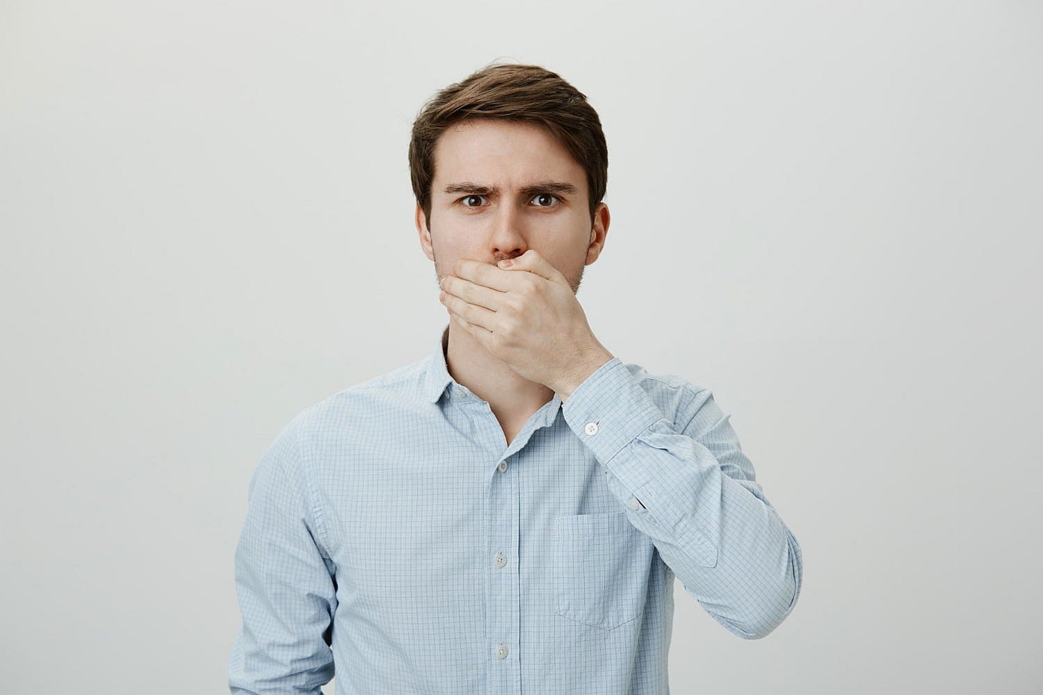 Shocked upset brunette man shut mouth with hand cause mouth breathing in Prosper or Colleyville, TX