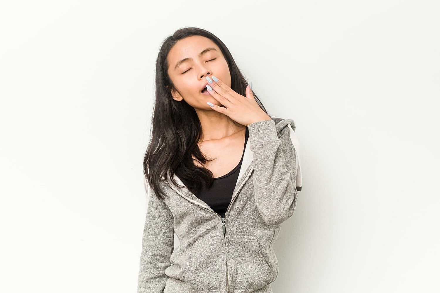 A woman slight yawn escaping as she covers her mouth with both hands looking very much the tired mouth breather in Prosper or Colleyville, TX