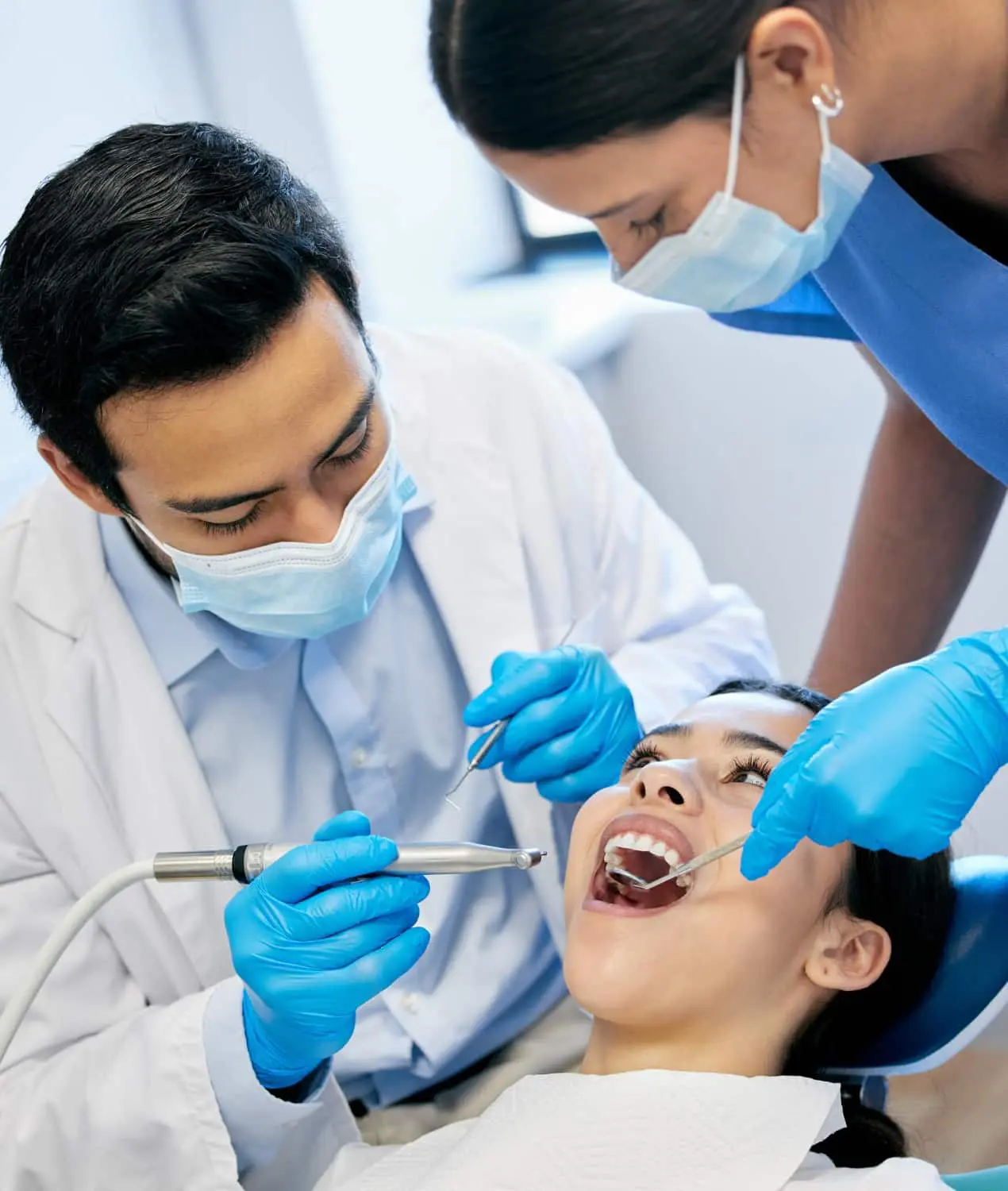 Dr. Mohammed Al-Zainal and Dr. Mo Idilbi: Orthodontist in Prosper TX At Wink Orthodontics in Prosper, TX, dentist and assistant in masks check a female patient’s mouth with instruments.