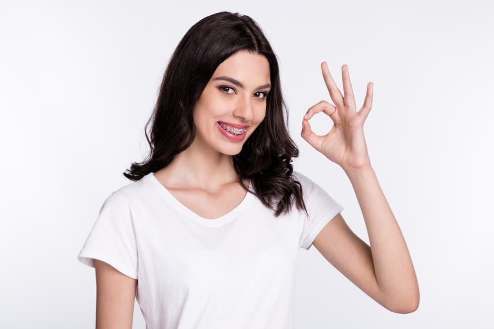 All PPO Insurance Plans Accepted: Orthodontist with Payment Plans Near You a woman showing OK hand sign to the camera after from an orthodontist in Prosper, TX