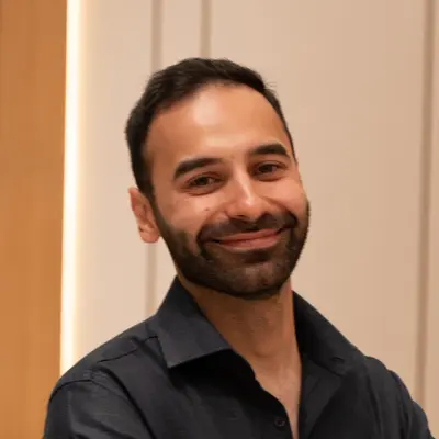 Dr. Mo of Wink Orthodontics in Prosper or Colleyville, TX, with short dark hair and a beard, smiles indoors at the camera.